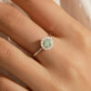 Halo ring worn on finger showing vivid green moissanite centerstone surrounded by sparkling white halo accent stones in sterling silver | D-Carats.