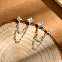 Close-up of a sterling silver double piercing earrings featuring two moissanite stud posts connected by delicate layered chains for a modern look | D-Carats.
