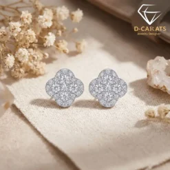 Close-up of sparkling moissanite earrings clover in platinum-plated silver resting on a neutral beige linen fabric surface