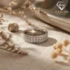 Moissanite eternity band ring in platinum-plated silver 23 Close-up side view of a silver eternity band ring with three rows of sparkling moissanite stones on a neutral fabric surface