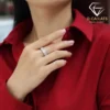Moissanite eternity band ring in platinum-plated silver 27 Close-up of a woman wearing a sparkling moissanite eternity band ring on her finger against a deep red fabric shirt