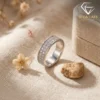 Moissanite eternity band ring in platinum-plated silver 22 Close-up of a platinum-plated silver eternity band ring with shimmering moissanite stones on a beige linen fabric surface