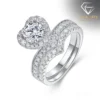 Moissanite Heart Halo Engagement Ring Set 27 Close-up of a silver heart shaped engagement ring set featuring a sparkling moissanite center stone with a diamond halo