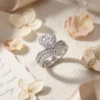 Moissanite Heart Halo Engagement Ring Set 23 Close-up side view of a silver heart shaped engagement ring set with shimmering moissanite stones on a linen surface