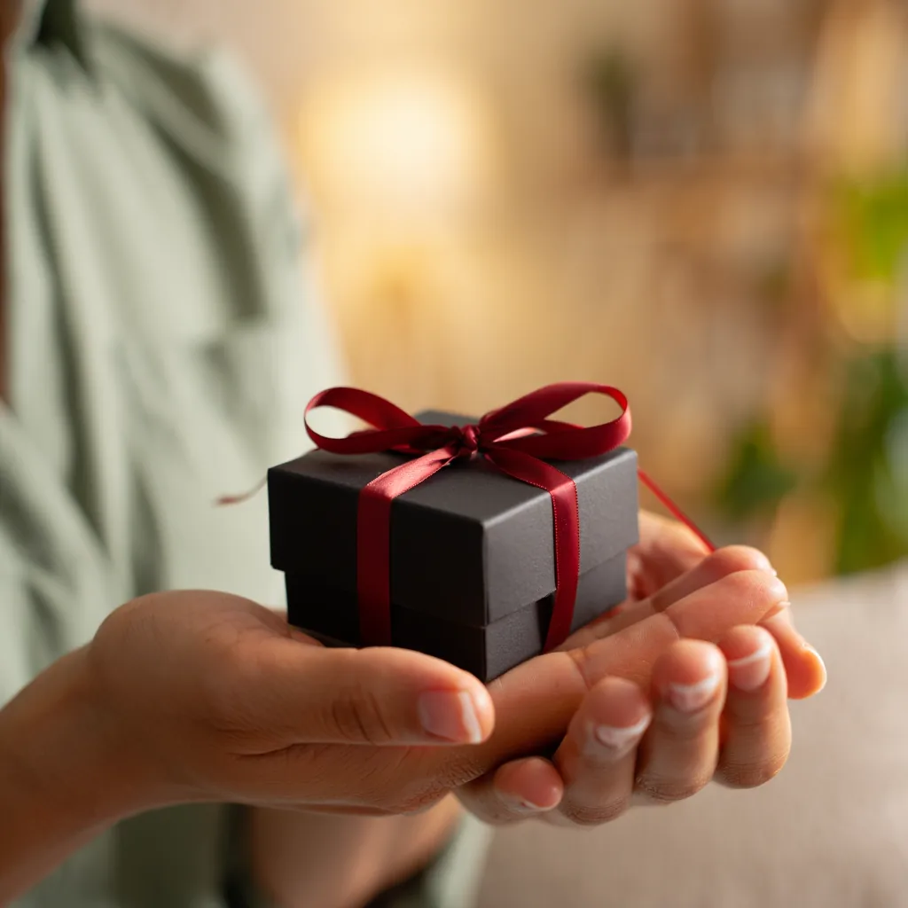 woman's hand gently holding a small closed jewelry gift box