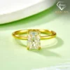 Close-up of a gold plated radiant cut engagement ring with a clear rectangular gemstone on a soft lime green surface