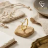 Gold plated silver radiant cut engagement ring balanced on a textured tan stone with soft linen and organic decor