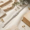 Close-up of a silver triple halo bracelet resting on a linen cloth beside a vintage book and dried botanical leaves