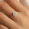 Halo ring worn on finger showing vivid green moissanite centerstone surrounded by sparkling white halo accent stones in sterling silver | D-Carats.