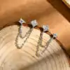 Close-up of a sterling silver double piercing earrings featuring two moissanite stud posts connected by delicate layered chains for a modern look | D-Carats.