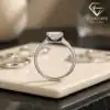 Side profile of a silver band featuring a horizontal east west emerald cut moissanite stone on a cream tray