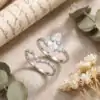 Marquise Moissanite Bridal Ring Set 29 Close-up of a silver marquise moissanite bridal ring set with a curved band resting on linen beside dried eucalyptus leaves