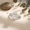 Marquise Moissanite Bridal Ring Set 17 Silver marquise moissanite bridal ring set with baguette accents and a curved band on beige linen with soft natural light
