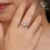 Halo Heart Ring 42 Close-up of a woman’s hand wearing a sparkling moissanite heart ring halo setting, showcasing the intricate pave band and brilliant center stone