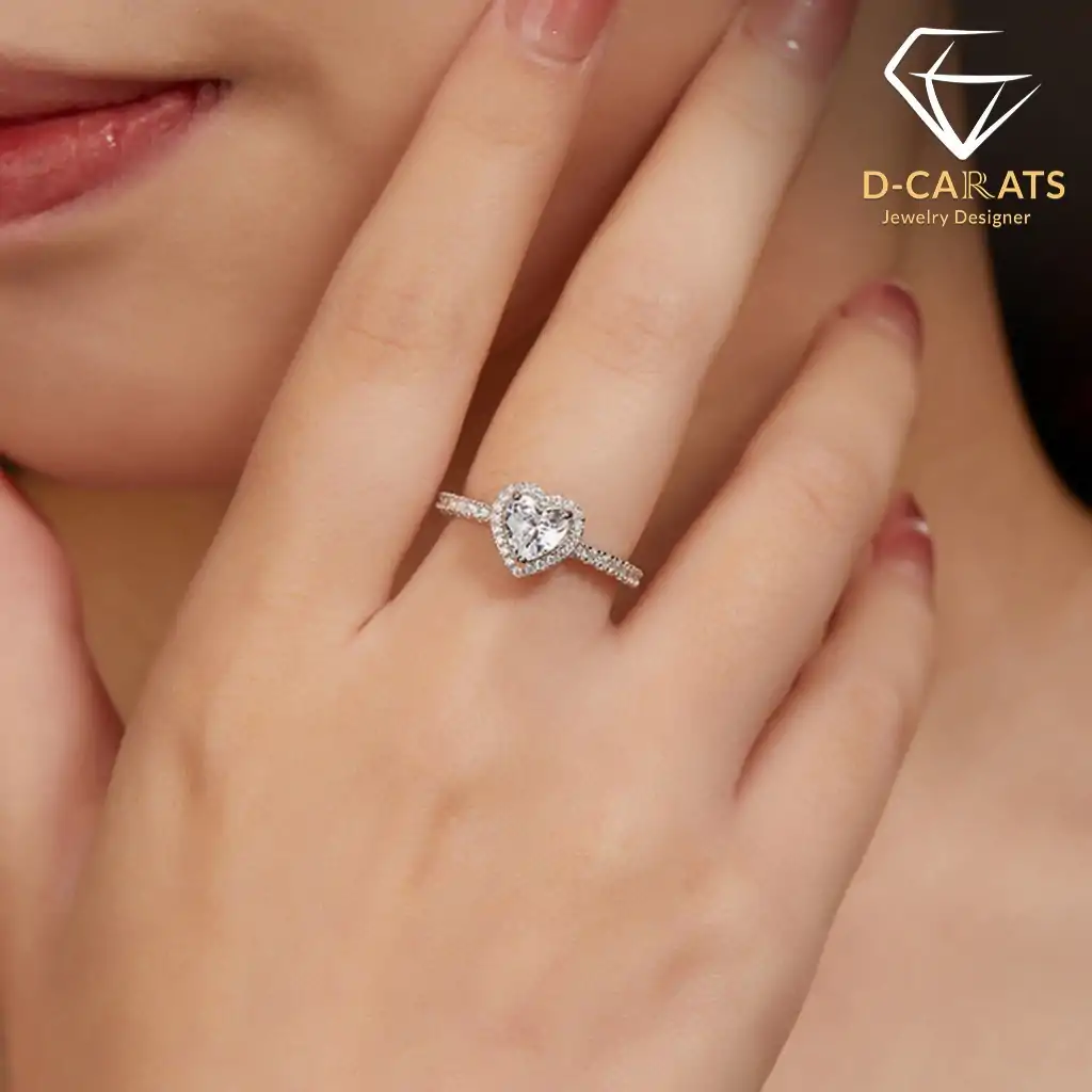 Halo Heart Ring 24 Close-up of a woman’s hand wearing a sparkling moissanite heart ring halo setting, showcasing the intricate pave band and brilliant center stone
