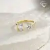 Close-up of a gold moissanite toi moi ring featuring one round and one emerald cut stone on a textured white stone base
