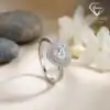 Close-up of a polished silver heart ring double halo with sparkling moissanite set against soft white flowers and stones