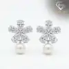 Pendientes colgantes de perla y plata con flor de circón 24 Plano detalle de pétalos de flor de circón brillante sobre elegantes pendientes colgantes de perla plateada con un suave resplandor luminoso