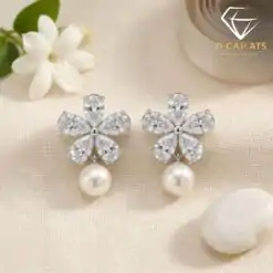 Close-up of silver pearl drop earrings featuring a sparkling zircon flower design resting on a textured cream fabric