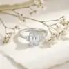 Three-stone emerald cut ring in 925 silver 18 Close-up of a three stone emerald cut silver ring nestled among delicate white dried flowers on textured cream paper