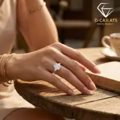 Close-up of a woman's hand wearing a silver three stone emerald cut ring resting on an open book at a rustic wooden table