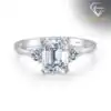 Three-stone emerald cut ring in 925 silver 16 Close-up of a polished silver three stone emerald cut ring featuring a large central gem and two smaller side diamonds