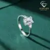 Three-stone emerald cut ring in 925 silver 21 Side view of a polished silver three stone emerald cut ring with clear crystals on a dark green velvet textile
