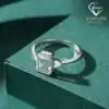 Three-stone emerald cut ring in 925 silver 20 Close-up of a three stone emerald cut silver ring with clear crystals resting on a dark green textured velvet surface