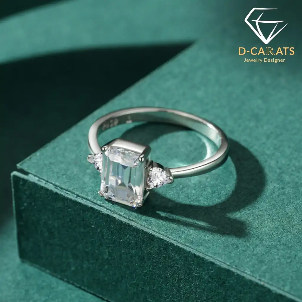 Three-stone emerald cut ring in 925 silver 10 Close-up of a three stone emerald cut silver ring with clear crystals resting on a dark green textured velvet surface